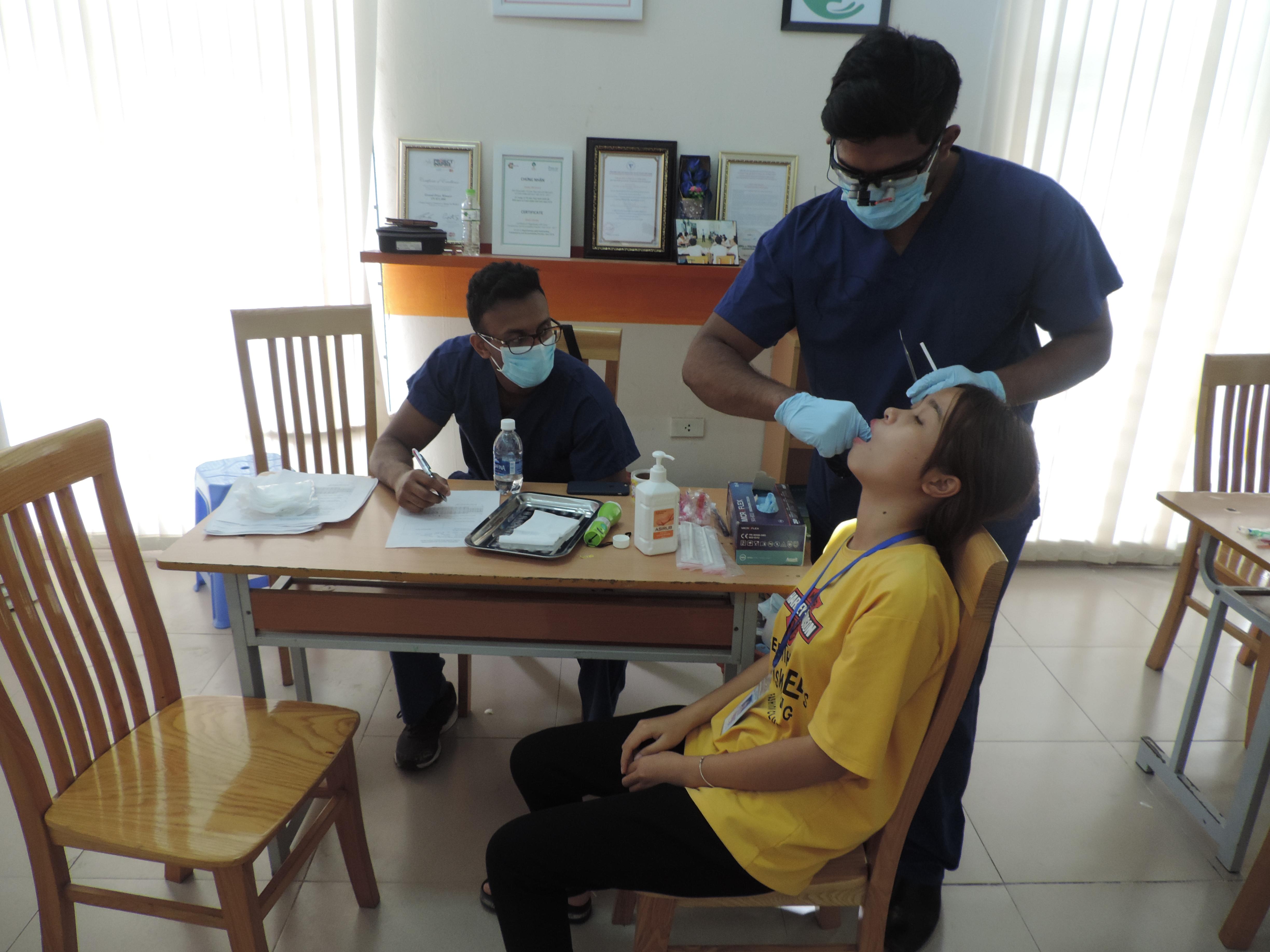 A Dentistry intern examines a patient under the supervision of a local dentist in Vietnam. A student doing a Dentistry placement in Vietnam examines a patient under supervision.